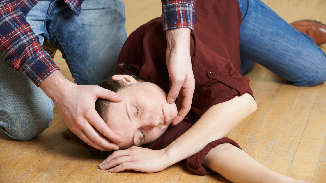 Man placing woman in the recovery position.